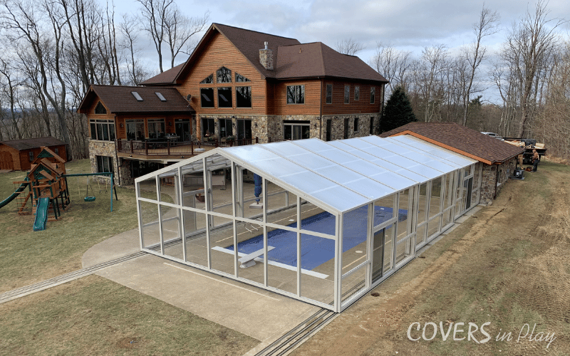 Wide view of large residential backyard pool enclosure and playground in Triadelphia, WV