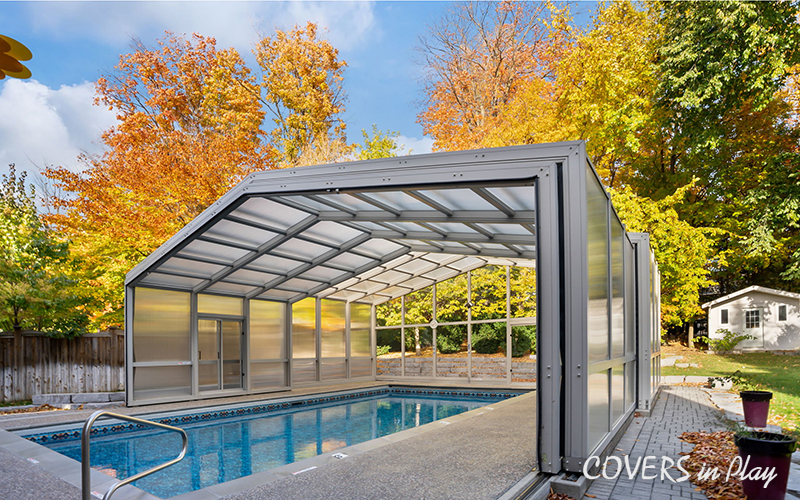 Exterior view of opened pool enclosure with frosted windows and trees surrounding the infrastructure