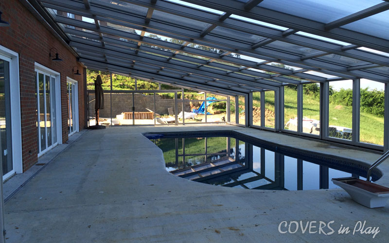 Interior view of a lean-to pool cover in Chester, VA, with patio room and
greenery in the background.