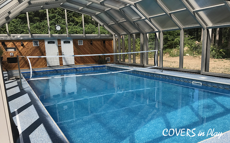 Interior view of a lean-to pool cover in Chester, VA, with patio room and
greenery in the background.