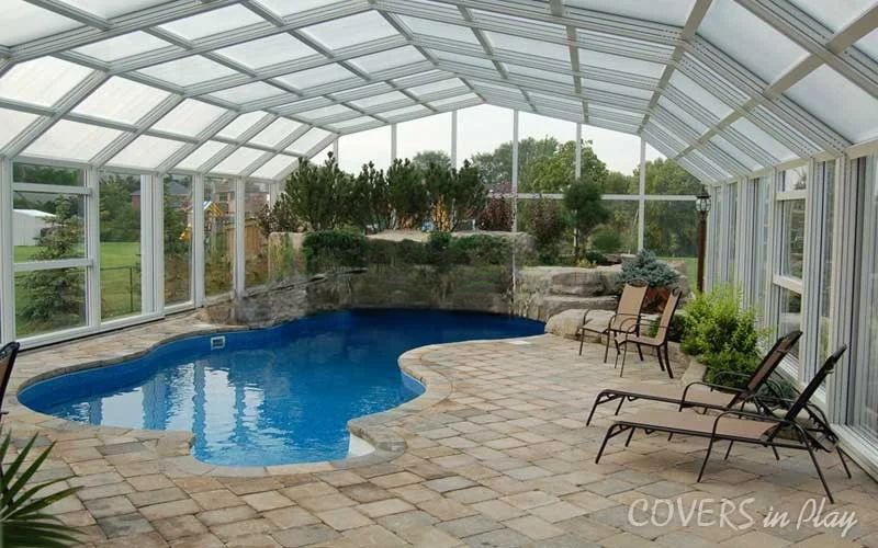 Interior center view of closed pool enclosure with plants and lawn chairs in Sharon