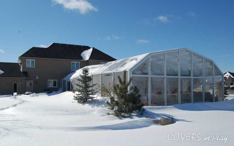 Exterior rear view of a covered outdoor pool in Sharon, ON, with snow on
the ground and around the enclosure.