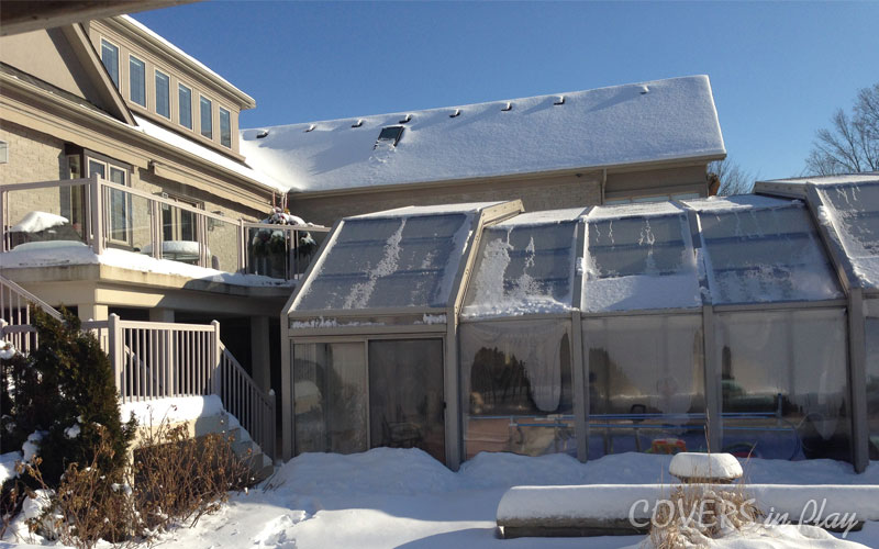 Exterior view of covered pool in Vaughn, ON, with snow on the group and on top of the enclosure.