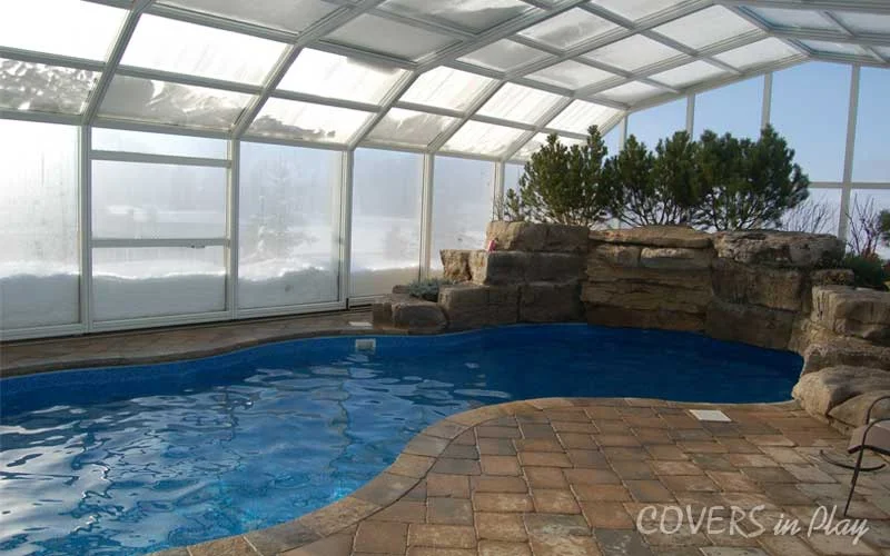 Interior side angle of a closed pool enclosure with a foot of snow outside the structure