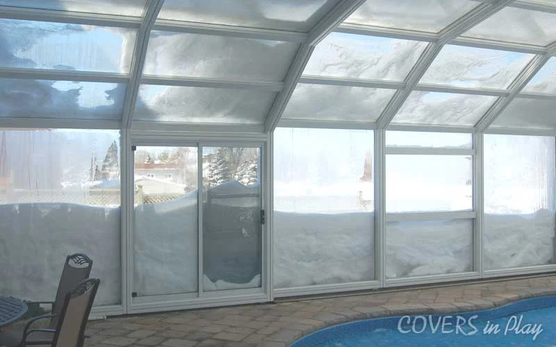 Close up view of the walls of a pool enclosure keeping feet of snow out, and the warm air inside.