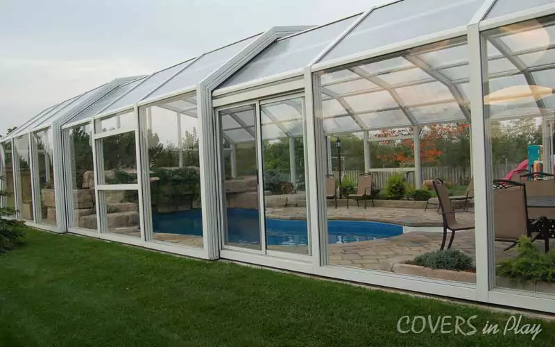 Exterior side view of closed pool enclosure, with the structure integrated into the surrounding backyard